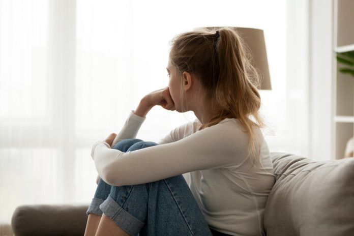 upset woman sitting on couch alone at home